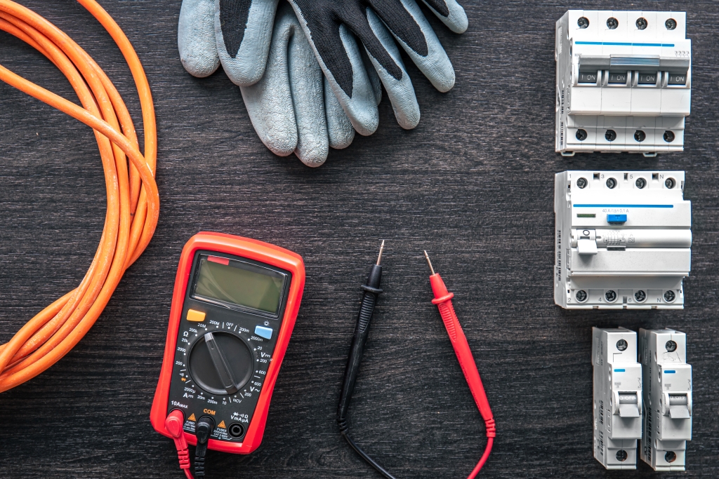 Different electrical tools on wooden background, flat lay.